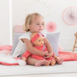 Peuter knuffelt Corolle babypop in roze outfit