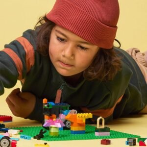 Kind speelt met kleurrijke LEGO blokjes op groene bouwplaat