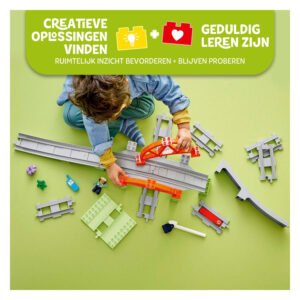 Kind bouwt met LEGO DUPLO treinrails en brugdelen op groene ondergrond