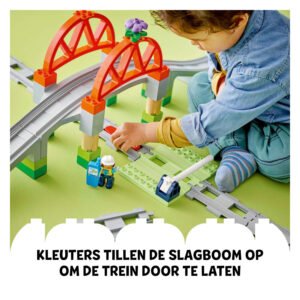 Peuter beweegt slagboom bij LEGO DUPLO treinbaan onder brug