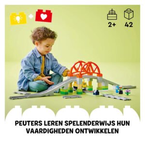 Peuter speelt met LEGO DUPLO treinbrug bouwset op groene achtergrond