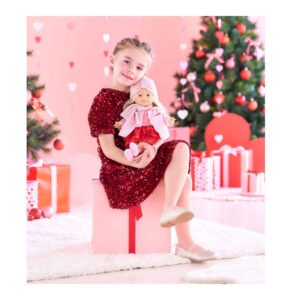 Meisje in feestjurk houdt Corolle pop vast voor kerstboom