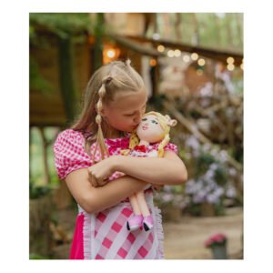 Meisje knuffelt Lappenpop Julia in roze geruite jurk in een bosrijke omgeving