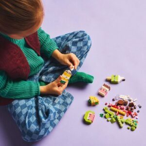 Kind bouwt LEGO figuren uit kleurrijke stenen van set met vrolijke voedselthema’s