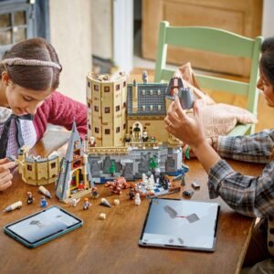 Twee kinderen bouwen LEGO Harry Potter Hogwarts kasteel met tablet instructies op tafel