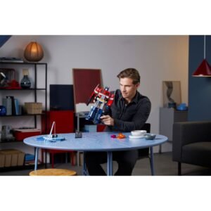 Volwassene speelt met LEGO Optimus Prime aan een tafel
