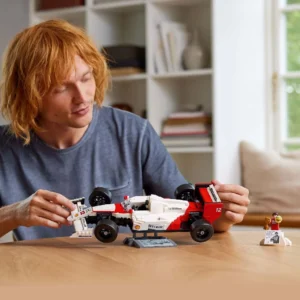 Man bouwt LEGO Icons McLaren Formule 1 auto aan tafel met Senna minifiguur