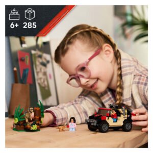 Meisje speelt met LEGO Jurassic World set aan tafel