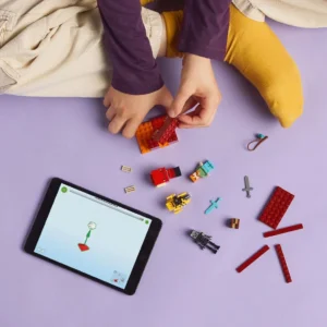 Kind bouwt LEGO Minecraft set met hulp van tablet op paarse achtergrond