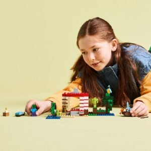 Meisje speelt met LEGO Minecraft TNT Jungle House op een gele achtergrond