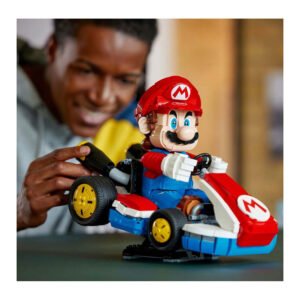 Man speelt met LEGO Super Mario Kart model met rode kart en Mario-figuur