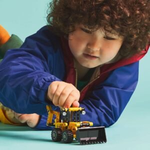 Kind speelt met LEGO Technic graaflaadmachine op blauwe vloer