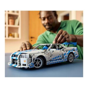 Man bestuurt LEGO Technic Nissan Skyline GT-R model met handbewegingen