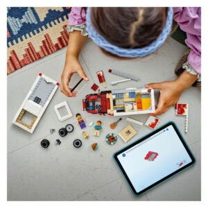 Kind bouwt LEGO City camper met tablet en onderdelen op de vloer