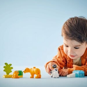 Peuter speelt met LEGO DUPLO pinguïns en leeuwen dierenfiguren op een blauwe achtergrond