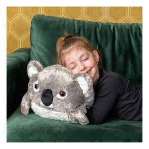 Kind ligt op groene bank en knuffelt schattige koala knuffel