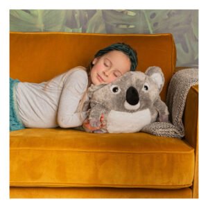 Meisje knuffelt zachte koala knuffel op okergele bank