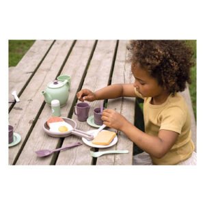 kind speelt met houten speelgoed servies en ontbijtset aan picknicktafel