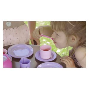 Meisje drinkt uit speelgoed servies tijdens theekransje buiten