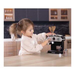 Meisje speelt met speelgoed espresso machine in keuken