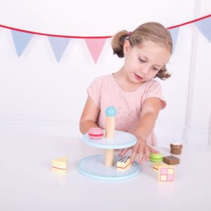 Kind speelt met houten taartstandaard en speelgoedgebak