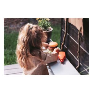 Kind speelt met houten speelgoed hamburgerset in de tuin