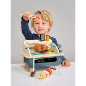 Jongen speelt met houten barbecue speelgoed voor kinderen