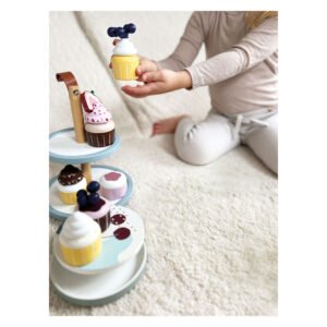 Kind speelt met houten cupcake speelgoed en taartstandaard