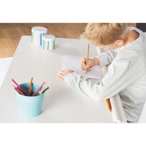 Jongen tekent met kleurpotloden aan een wit kinderbureau