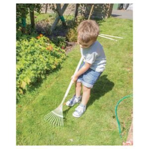 Kind harkt gras in de tuin met een kinderhark