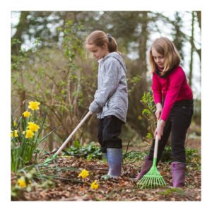 twee kinderen die tuinbladeren harken tussen bloemen