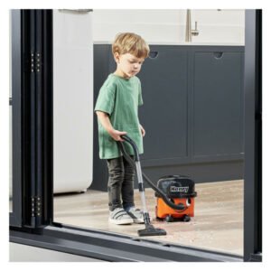 Kind speelt met Henry speelgoed stofzuiger op keukenvloer