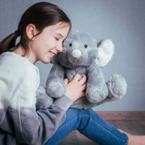 Grijze knuffelolifant in de armen van een glimlachend kind