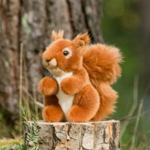 Pluche eekhoorn knuffel op boomstronk tussen bomen
