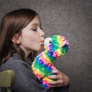 Meisje geeft een kus aan regenboog lama knuffel met zachte vacht