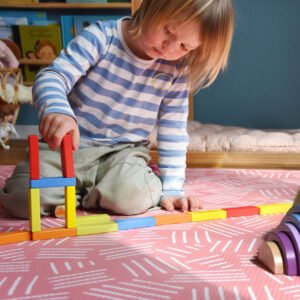 Kind speelt met kleurrijk houten regenboog stapel speelgoed op speelmat